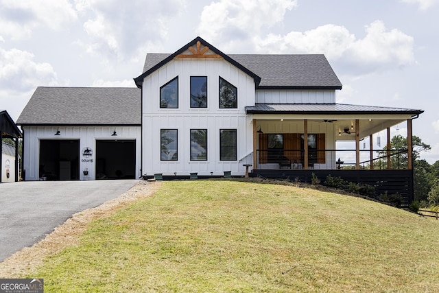 modern inspired farmhouse featuring a porch, a garage, ceiling fan, and a front lawn