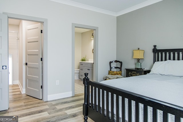 bedroom featuring light hardwood / wood-style floors, ensuite bath, and crown molding