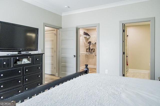 bedroom with light hardwood / wood-style flooring, ensuite bath, a spacious closet, and crown molding