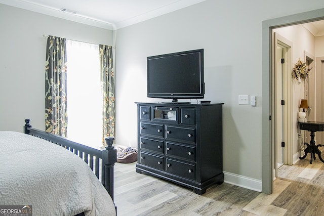 bedroom with light hardwood / wood-style flooring and crown molding