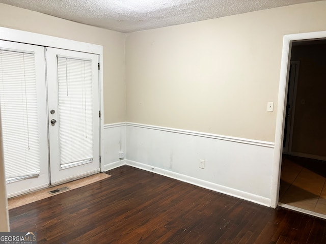 empty room featuring a textured ceiling and dark hardwood / wood-style floors