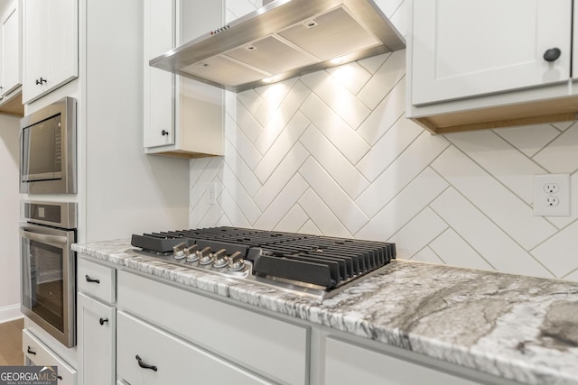 kitchen with white cabinets, range hood, stainless steel appliances, and decorative backsplash