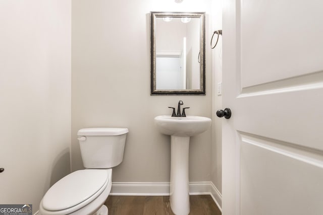 half bath with wood finished floors, toilet, and baseboards