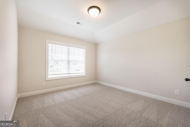 carpeted spare room with lofted ceiling and baseboards