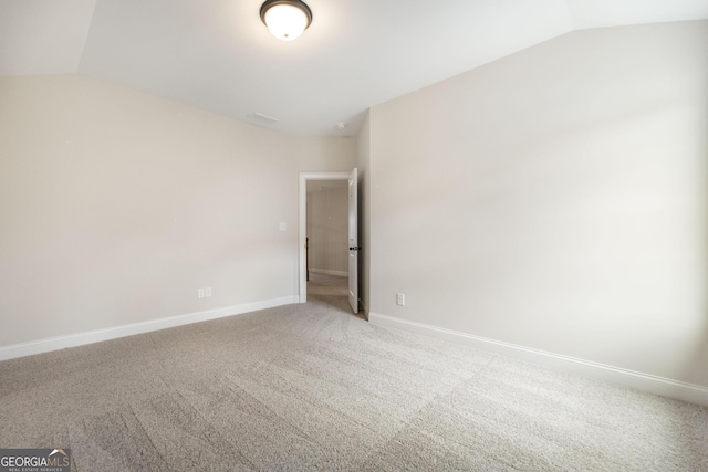 unfurnished room featuring baseboards, vaulted ceiling, and carpet flooring