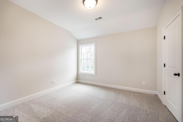 carpeted empty room featuring lofted ceiling, visible vents, and baseboards