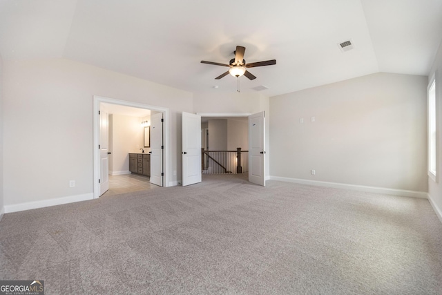 unfurnished bedroom with light colored carpet, vaulted ceiling, visible vents, and baseboards