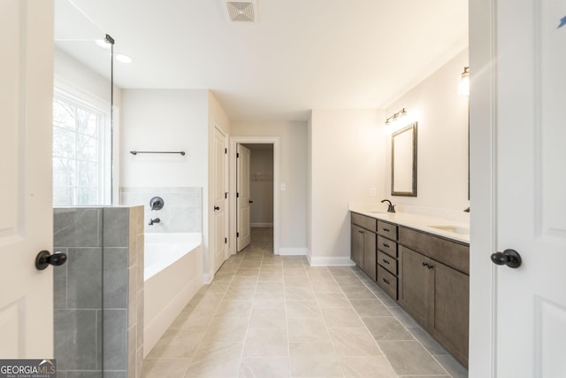 full bath featuring a garden tub, double vanity, visible vents, a spacious closet, and a sink