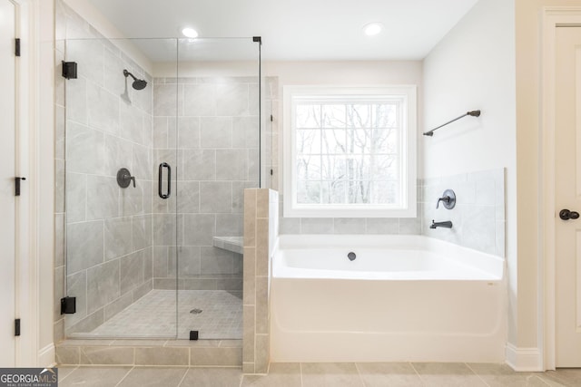 full bath with a stall shower, tile patterned floors, and a bath