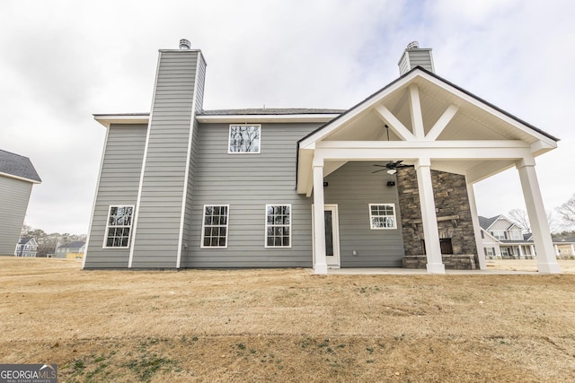 back of property featuring a ceiling fan, a lawn, and a chimney