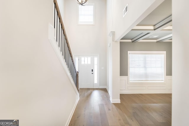 foyer entrance featuring a wainscoted wall, plenty of natural light, wood finished floors, and visible vents