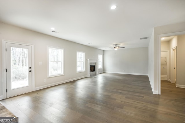 unfurnished living room with baseboards, visible vents, dark wood finished floors, and a fireplace