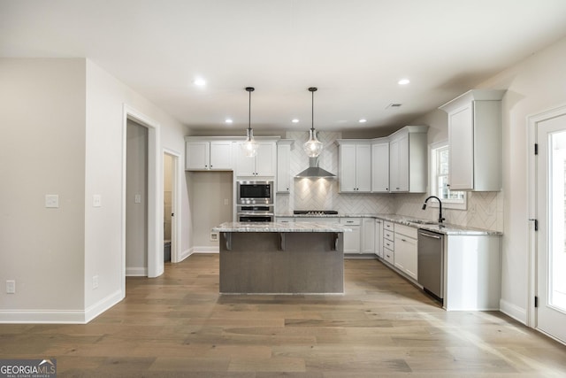 kitchen with decorative backsplash, appliances with stainless steel finishes, a center island, light wood-type flooring, and a sink