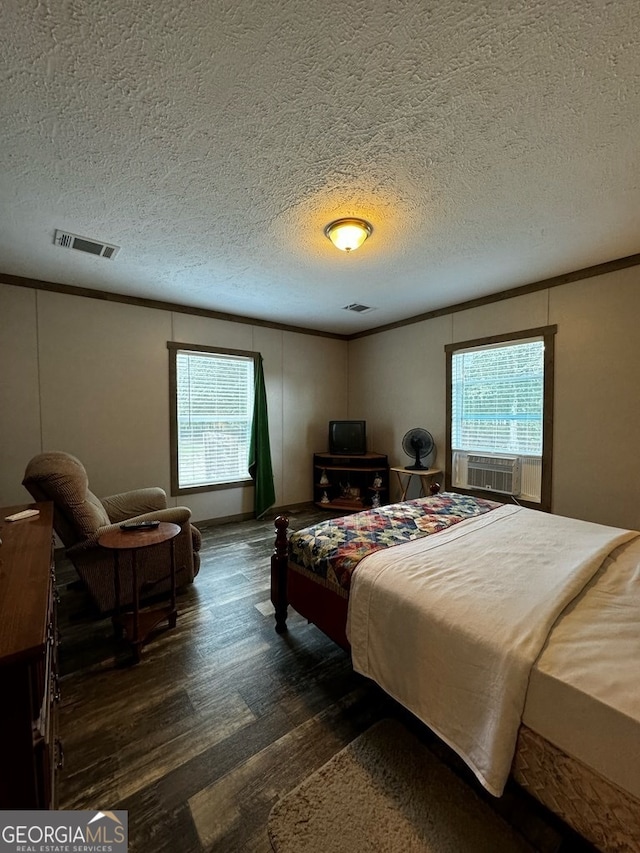 bedroom with a textured ceiling, dark hardwood / wood-style floors, and multiple windows