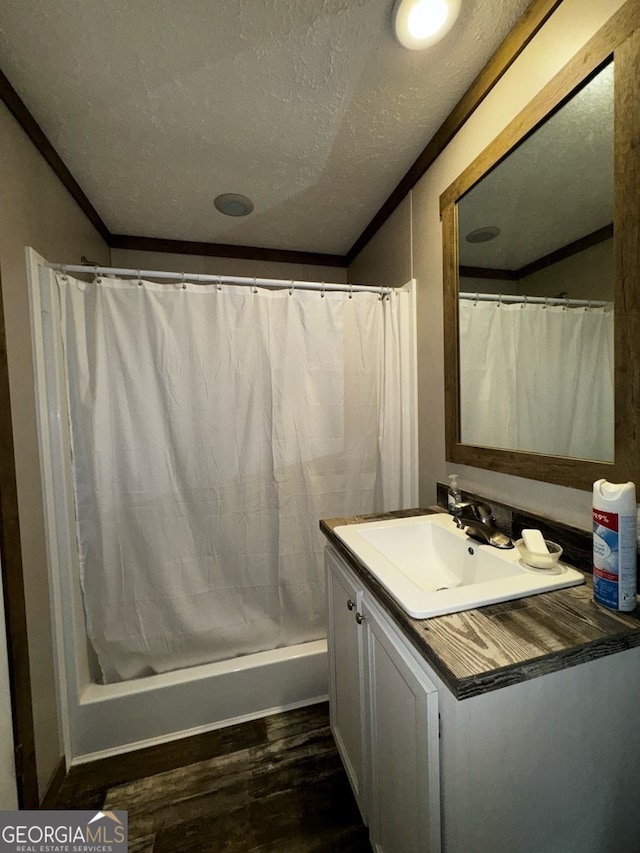 bathroom with vanity, a textured ceiling, shower / tub combo with curtain, ornamental molding, and hardwood / wood-style floors