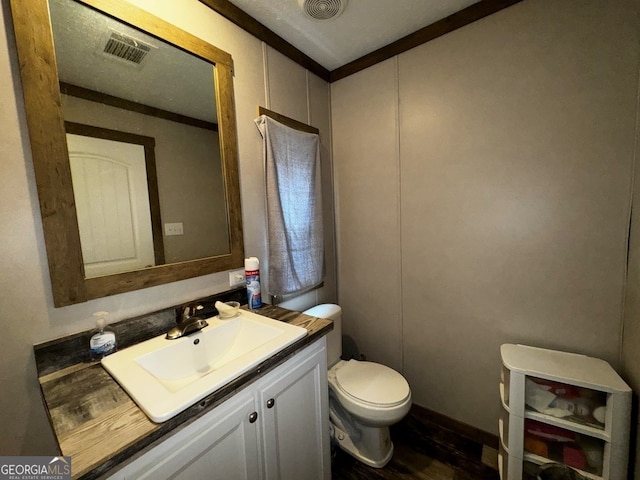 bathroom with vanity, crown molding, and toilet