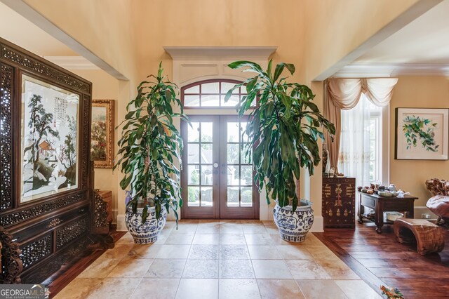 foyer featuring crown molding, light hardwood / wood-style floors, and french doors