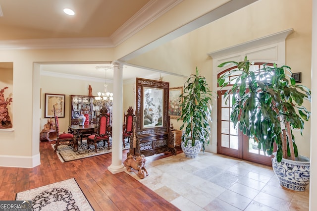 foyer with ornamental molding, hardwood / wood-style floors, a chandelier, and ornate columns