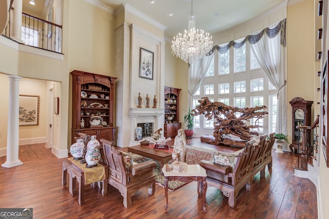 living room featuring a high ceiling, decorative columns, and hardwood / wood-style flooring