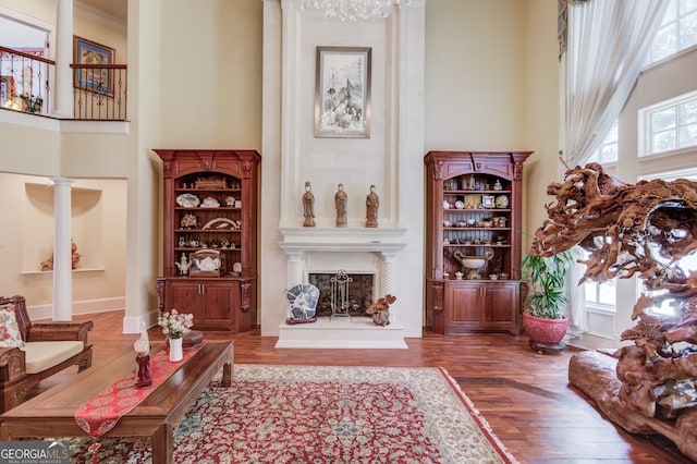 sitting room featuring decorative columns, a towering ceiling, hardwood / wood-style floors, and plenty of natural light