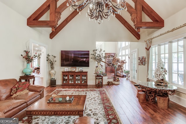 living room with wood-type flooring, an inviting chandelier, high vaulted ceiling, and a wealth of natural light