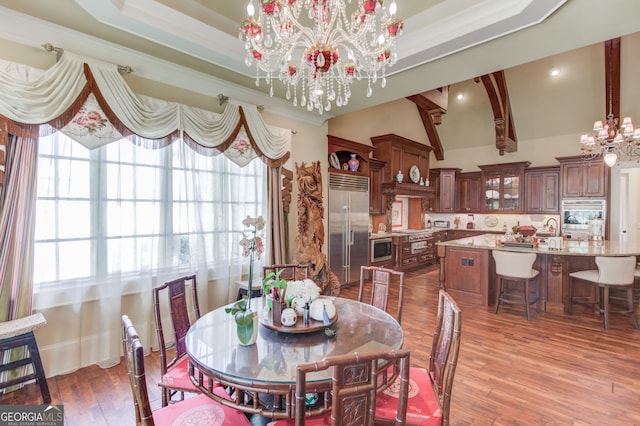 dining room with wood-type flooring, an inviting chandelier, lofted ceiling, and crown molding