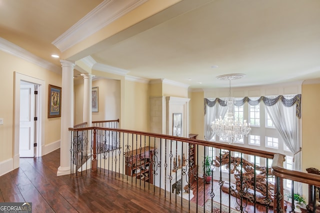 hallway with an inviting chandelier, decorative columns, ornamental molding, and dark hardwood / wood-style flooring