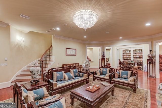 living room featuring wood-type flooring, crown molding, and a chandelier