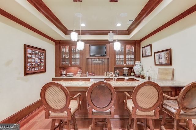 bar featuring light stone countertops, light wood-type flooring, decorative light fixtures, and crown molding