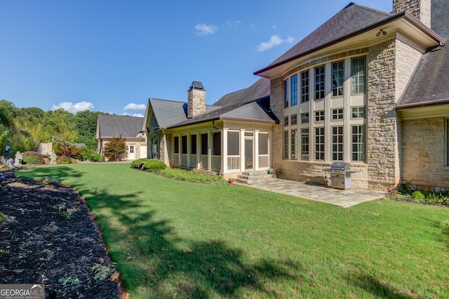 back of property featuring a sunroom, a patio, and a yard