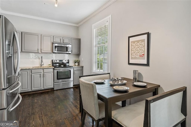 kitchen featuring backsplash, gray cabinetry, dark hardwood / wood-style flooring, and appliances with stainless steel finishes