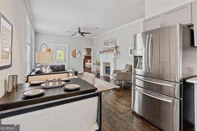 kitchen featuring ceiling fan, dark wood-type flooring, light stone counters, stainless steel fridge, and ornamental molding