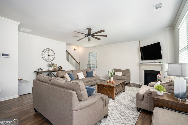 living room featuring wood-type flooring, crown molding, and ceiling fan