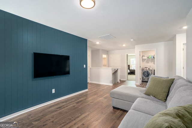 living room with washer / dryer, dark wood-type flooring, and wood walls