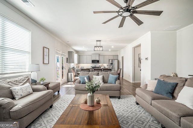 living room with ornamental molding, light hardwood / wood-style floors, and ceiling fan with notable chandelier