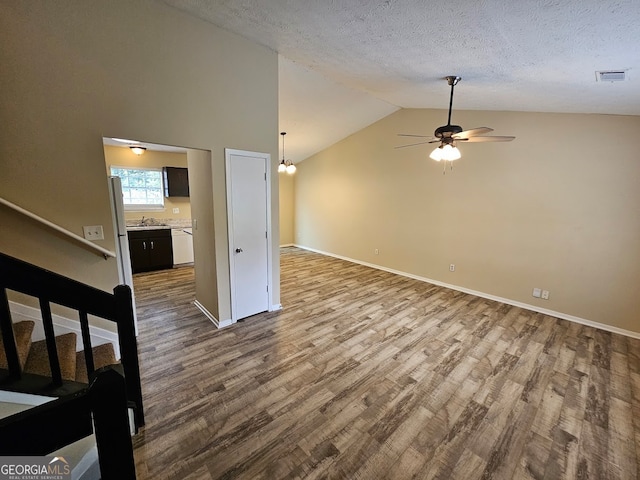 unfurnished living room featuring vaulted ceiling, hardwood / wood-style floors, ceiling fan, and sink