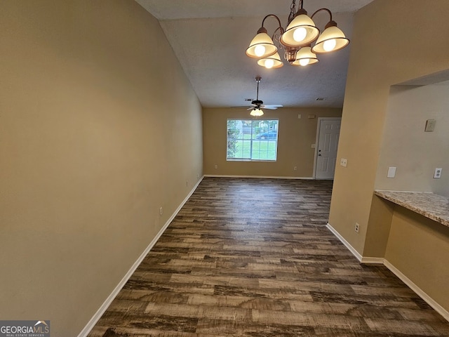 unfurnished dining area featuring ceiling fan with notable chandelier and dark wood-type flooring