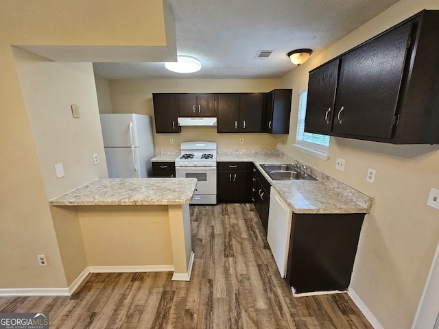 kitchen with white appliances, kitchen peninsula, light wood-type flooring, dark brown cabinetry, and sink