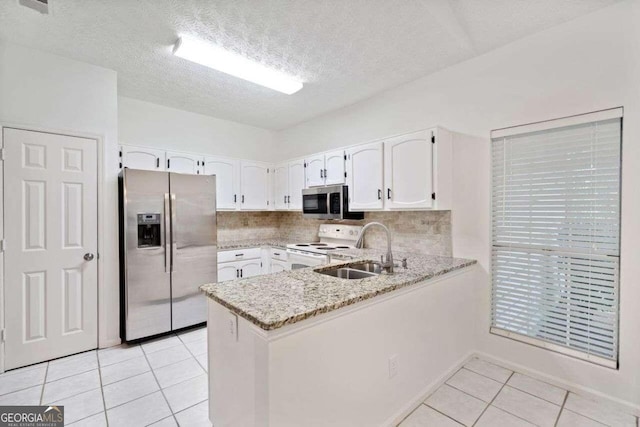 kitchen with appliances with stainless steel finishes, backsplash, kitchen peninsula, and white cabinetry