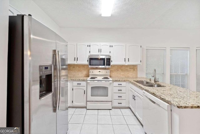 kitchen with white cabinets, sink, kitchen peninsula, backsplash, and appliances with stainless steel finishes