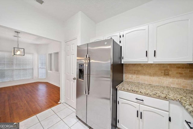 kitchen with a textured ceiling, white cabinets, light hardwood / wood-style flooring, decorative light fixtures, and stainless steel fridge