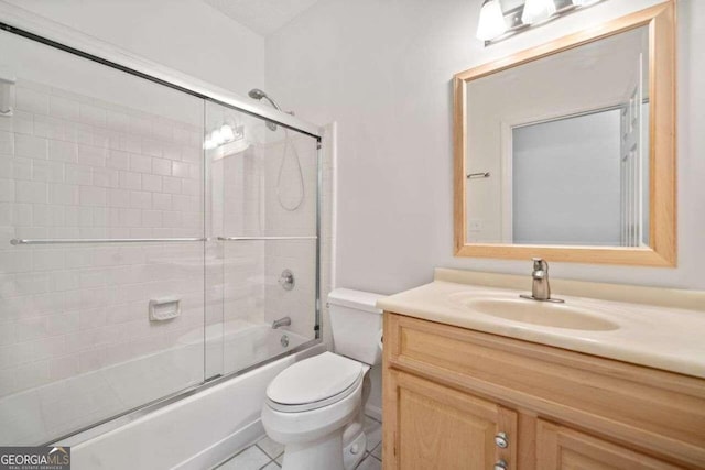 full bathroom with bath / shower combo with glass door, vanity, tile patterned flooring, and toilet