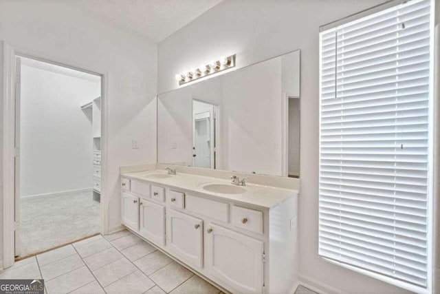 bathroom featuring vanity, a healthy amount of sunlight, a textured ceiling, and tile patterned floors