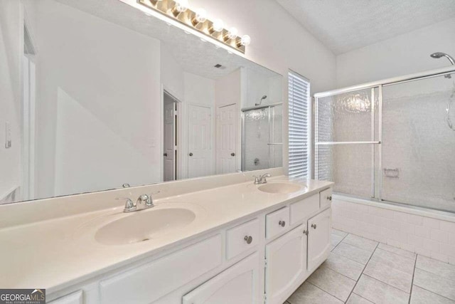 bathroom with bath / shower combo with glass door, vanity, a textured ceiling, and tile patterned floors