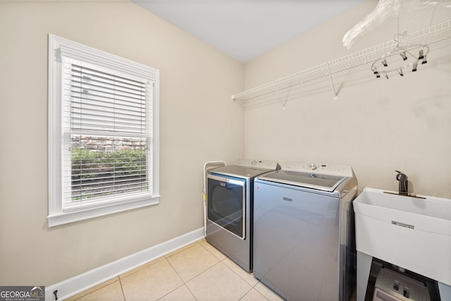 laundry area with washing machine and dryer, light tile patterned floors, and sink