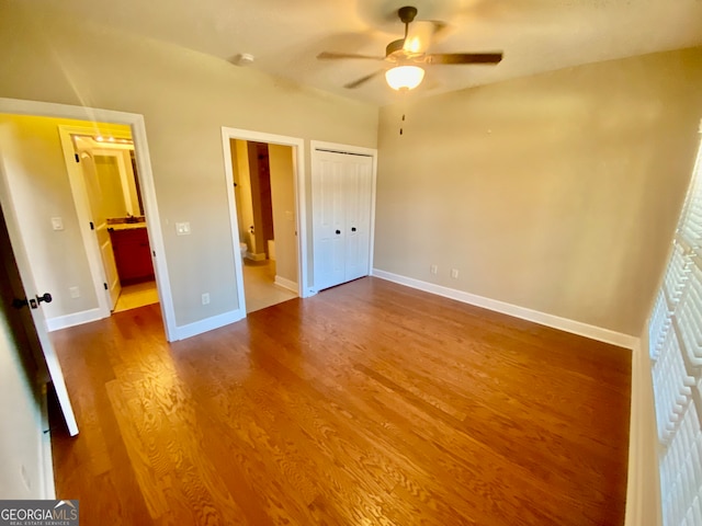 unfurnished bedroom with hardwood / wood-style flooring, ensuite bathroom, ceiling fan, and a closet