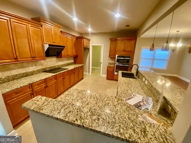 kitchen with stainless steel double oven, light stone counters, pendant lighting, black electric stovetop, and light tile patterned floors