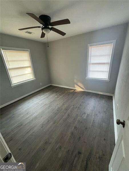 empty room with ceiling fan and dark hardwood / wood-style floors