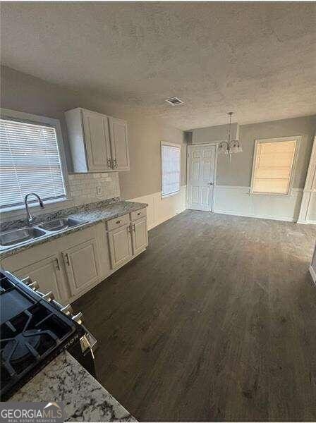 kitchen featuring pendant lighting, sink, a chandelier, white cabinetry, and dark hardwood / wood-style floors