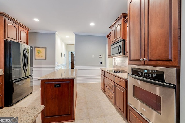 kitchen with light stone countertops, a center island, ornamental molding, and black appliances